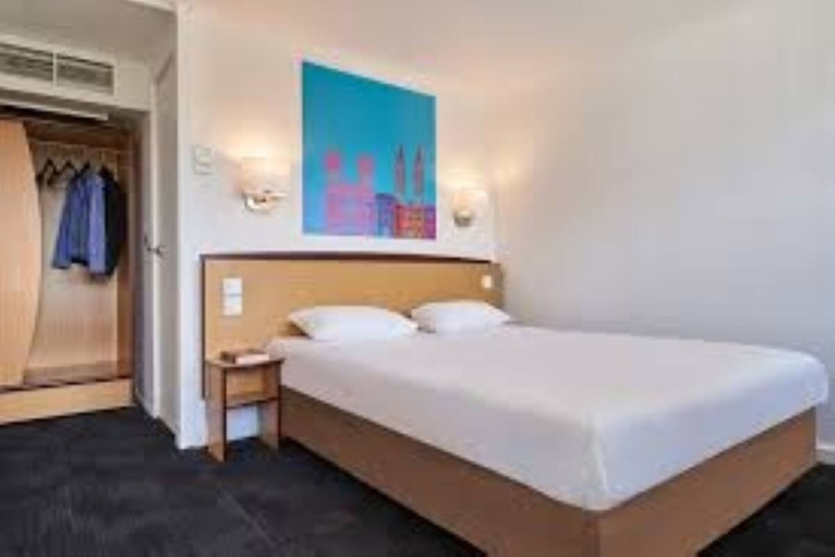 Une chambre d’hôtel avec un lit, une table de chevet et une armoire.