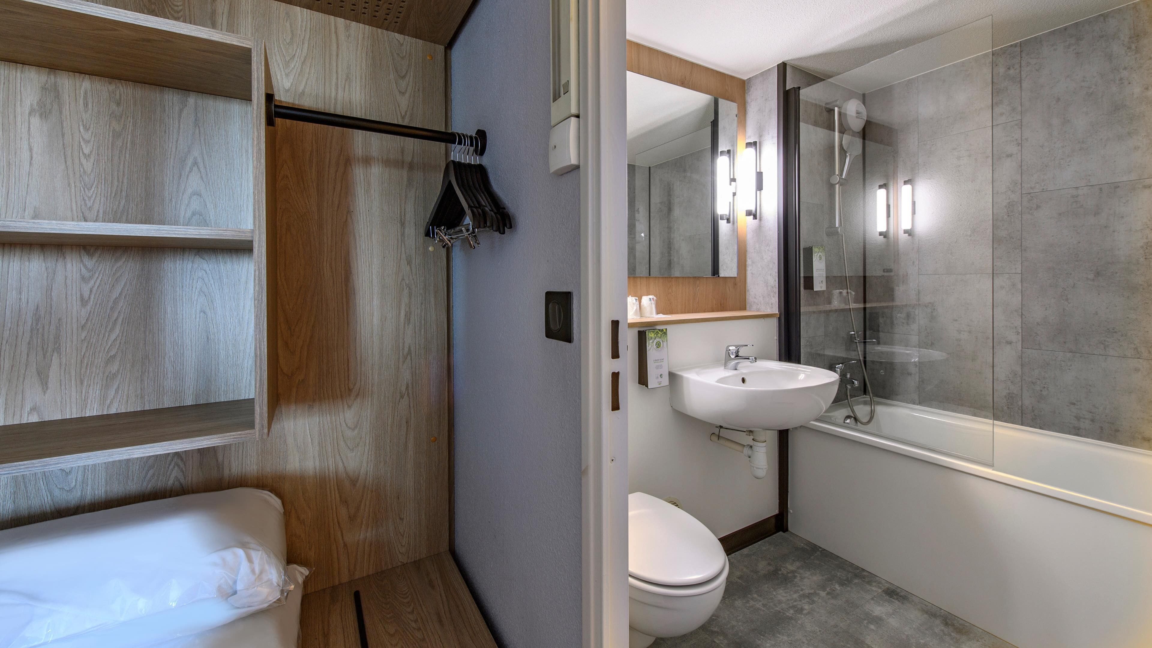 A modern bathroom with a wooden vanity, a white sink, a glass-enclosed shower, and a toilet.