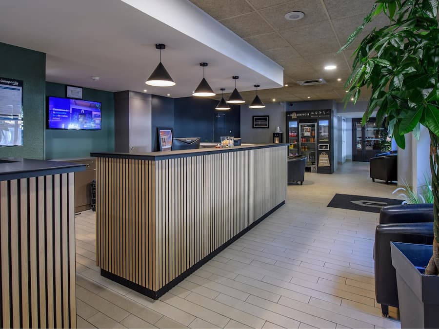 A reception area with a wooden reception desk, a TV screen, and a potted plant.