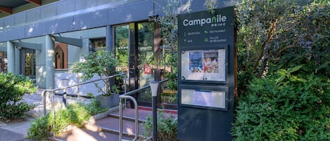 A building entrance with a sign for 'Camparile Prime' indicating a restaurant, reception, bar, and meeting rooms.