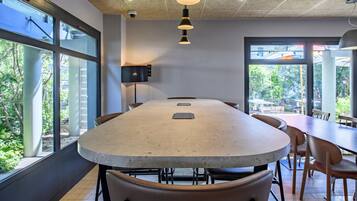 Un salón de conferencias con una gran mesa, sillas y ventanas amplias que dan a vistas del exterior.