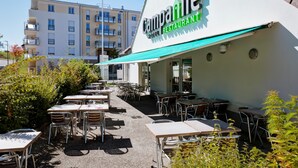A hotel restaurant with outdoor seating and a view of the surrounding buildings. - Campanile Geneve - Ferney-Voltaire (Ferney-Voltaire)