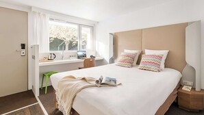 A modern hotel room with a large bed, a desk with a laptop, and a window with a view of trees. - Campanile Geneve - Ferney-Voltaire (Ferney-Voltaire)