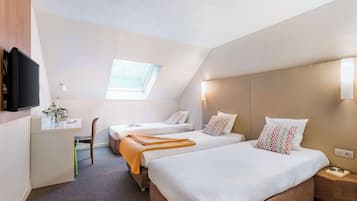 A hotel room with two beds, a desk, a TV, and a window.