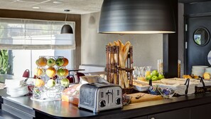 A breakfast buffet setup with a toaster, fruit, bread, and condiments. - Campanile Geneve - Ferney-Voltaire (Ferney-Voltaire)