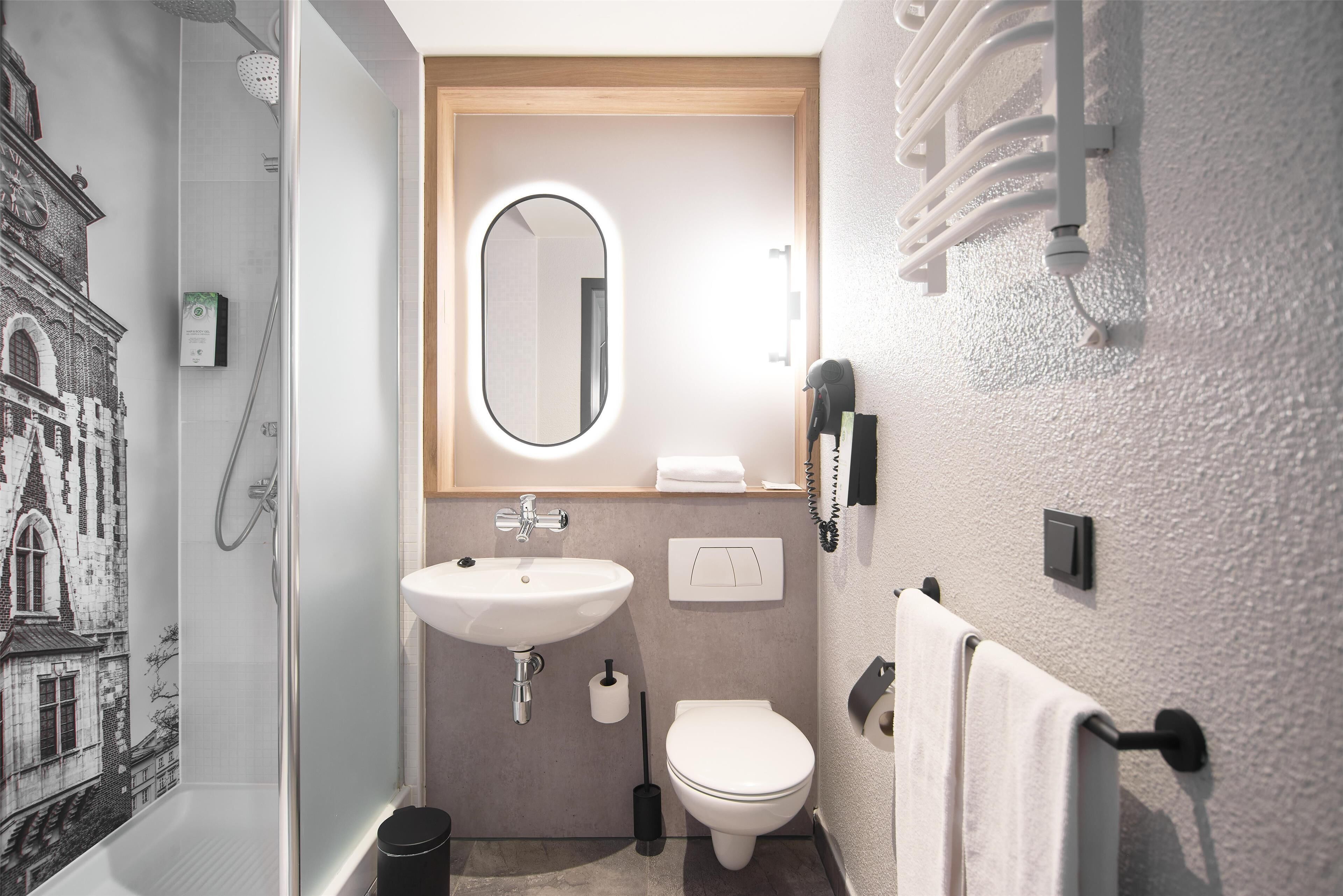 A bathroom with a shower, sink, toilet, and a mirror.