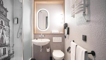A bathroom with a shower, sink, toilet, and a mirror.