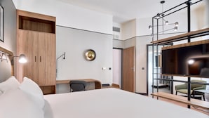 Une chambre d’hôtel moderne équipée d’un grand lit, d’un bureau, d’une chaise, d’une télévision et d’une armoire.