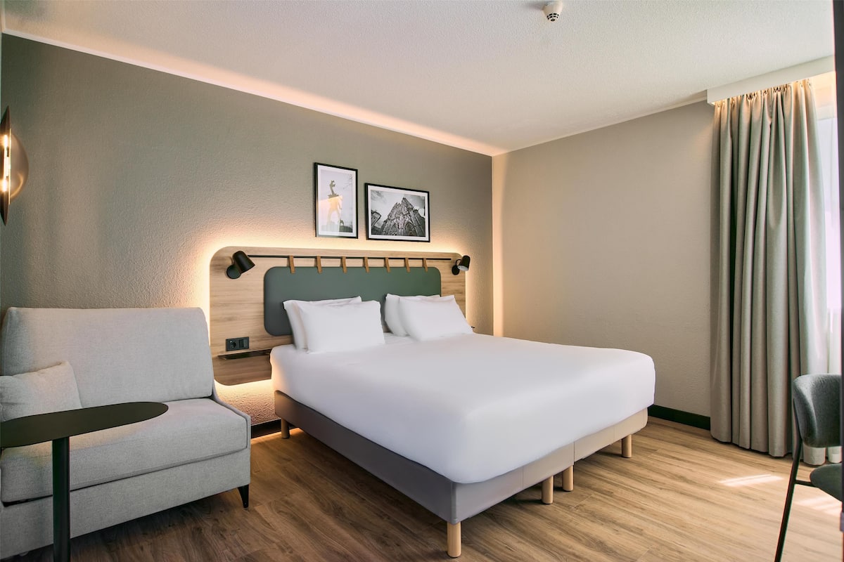 Een moderne hotelkamer met een groot bed, een bank en een klein tafeltje.
