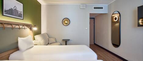 Una habitación de hotel con una cama grande, una mesita pequeña, un espejo en la pared y un cuadro de un castillo.