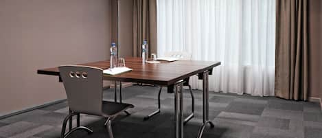 A conference room with a wooden table, two chairs, and a large window with curtains.