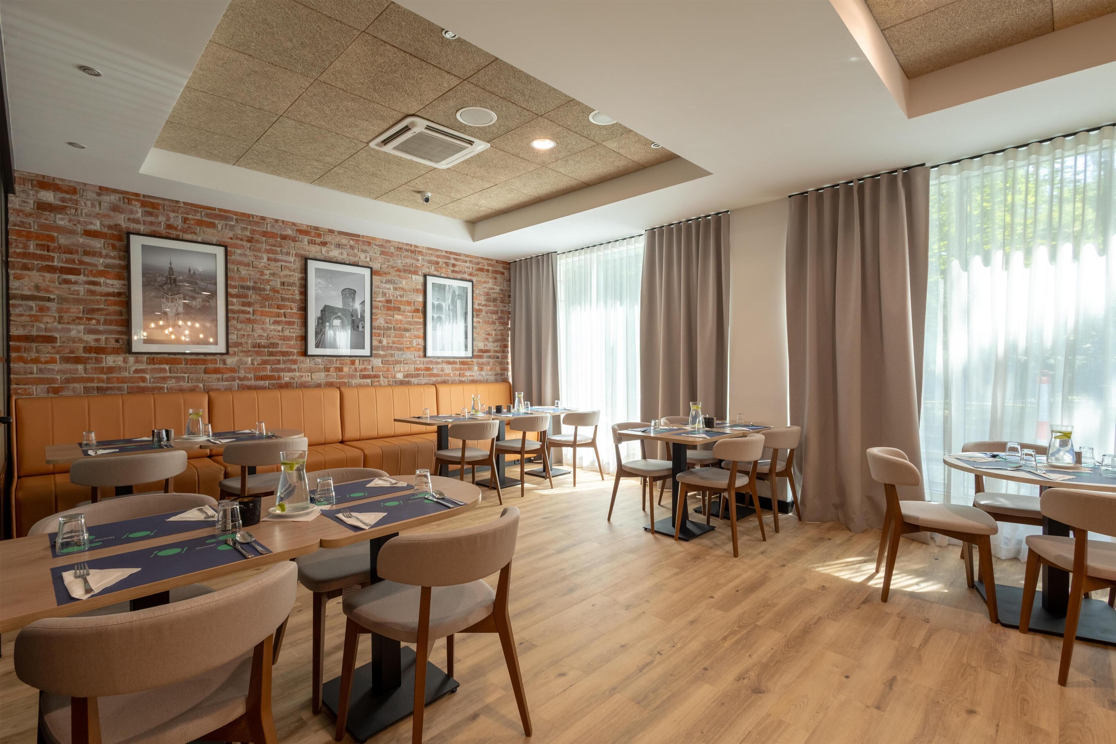 Un comedor moderno con paredes de ladrillo, piso de madera y una combinación de mesas redondas y cuadradas.