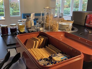 A breakfast bar with bread, butter, jam, and cereal.