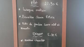Un tableau noir affiche la liste des plats et les prix du petit-déjeuner.