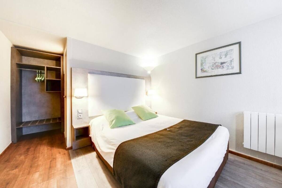 A bedroom with a bed, bedside lamps, a radiator, and a wardrobe.