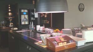 Eine moderne Küche mit einer zentralen Kochinsel, ausgestattet mit einer Kaffeemaschine, Tee-Station und verschiedenen Küchengeräten.