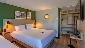 A hotel room with a large bed, two bedside lamps, a wall-mounted light, and a small table with a remote control. - Campanile NATURE - Grenoble Nord - Saint-Egrève (Saint-Egreve)