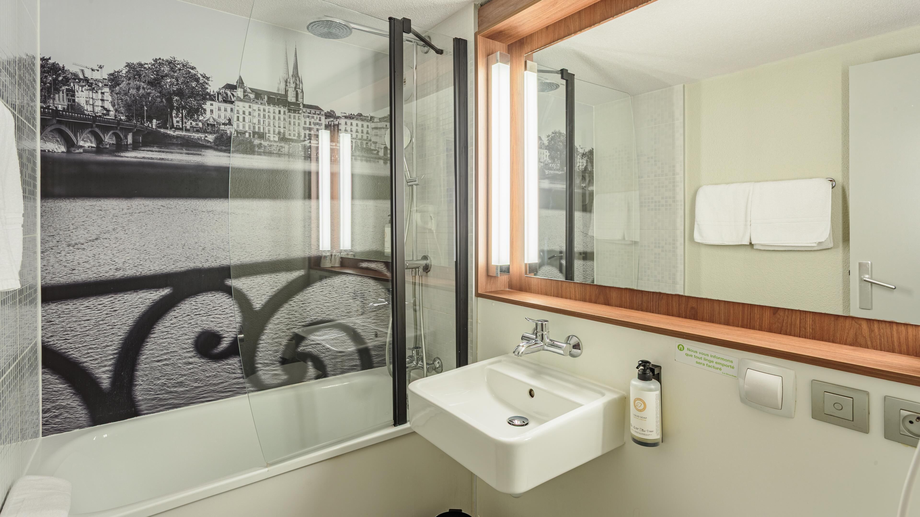Un baño con cabina de ducha de vidrio, un lavabo y un espejo con marco de madera.