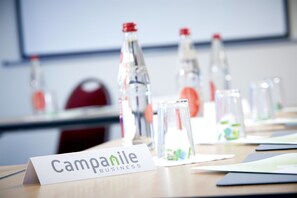 A conference table with a nameplate reading "Campanile Business" and several water bottles.