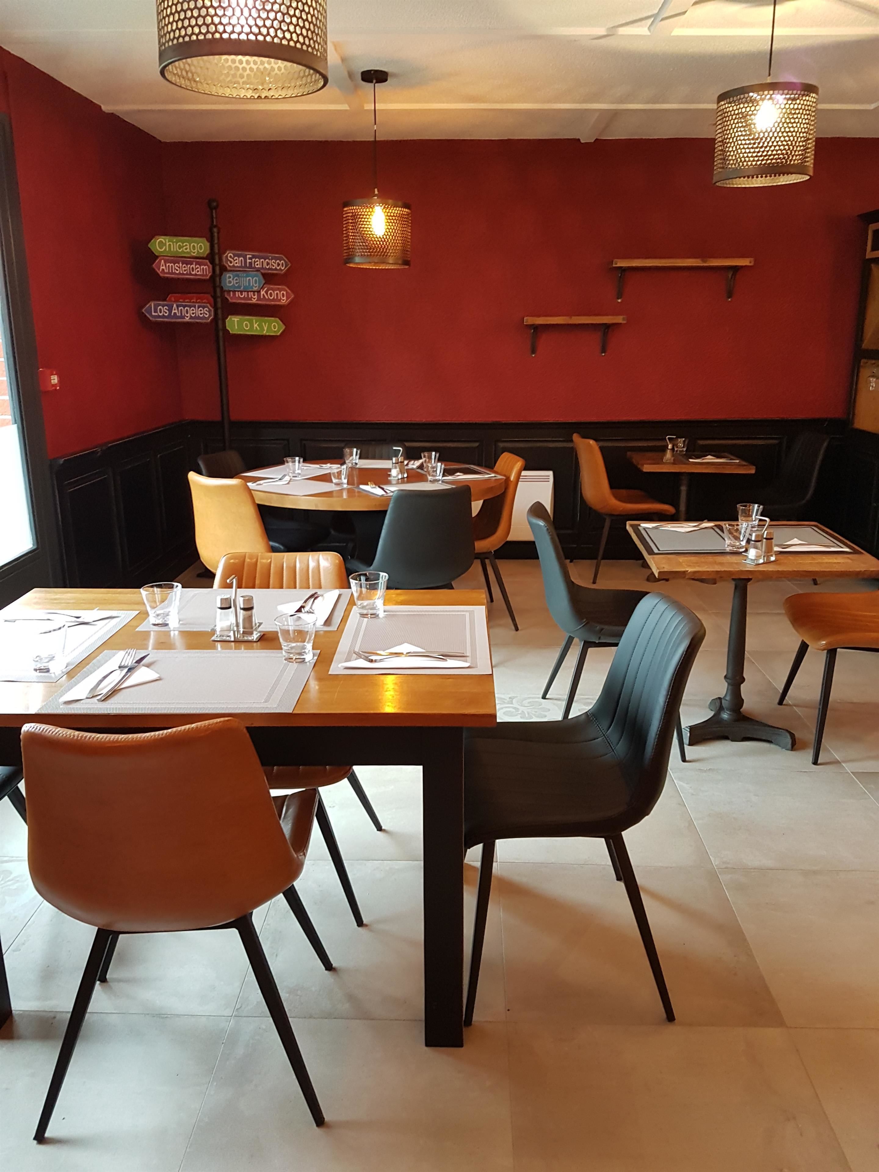 Ein Restaurantinneres mit Sitzboxen und Tischen, roten Wänden und hängenden Lampen.