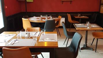 Ein Restaurantinneres mit Sitzboxen und Tischen, roten Wänden und hängenden Lampen.