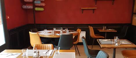 A restaurant interior with booths and tables, red walls, and hanging lights.