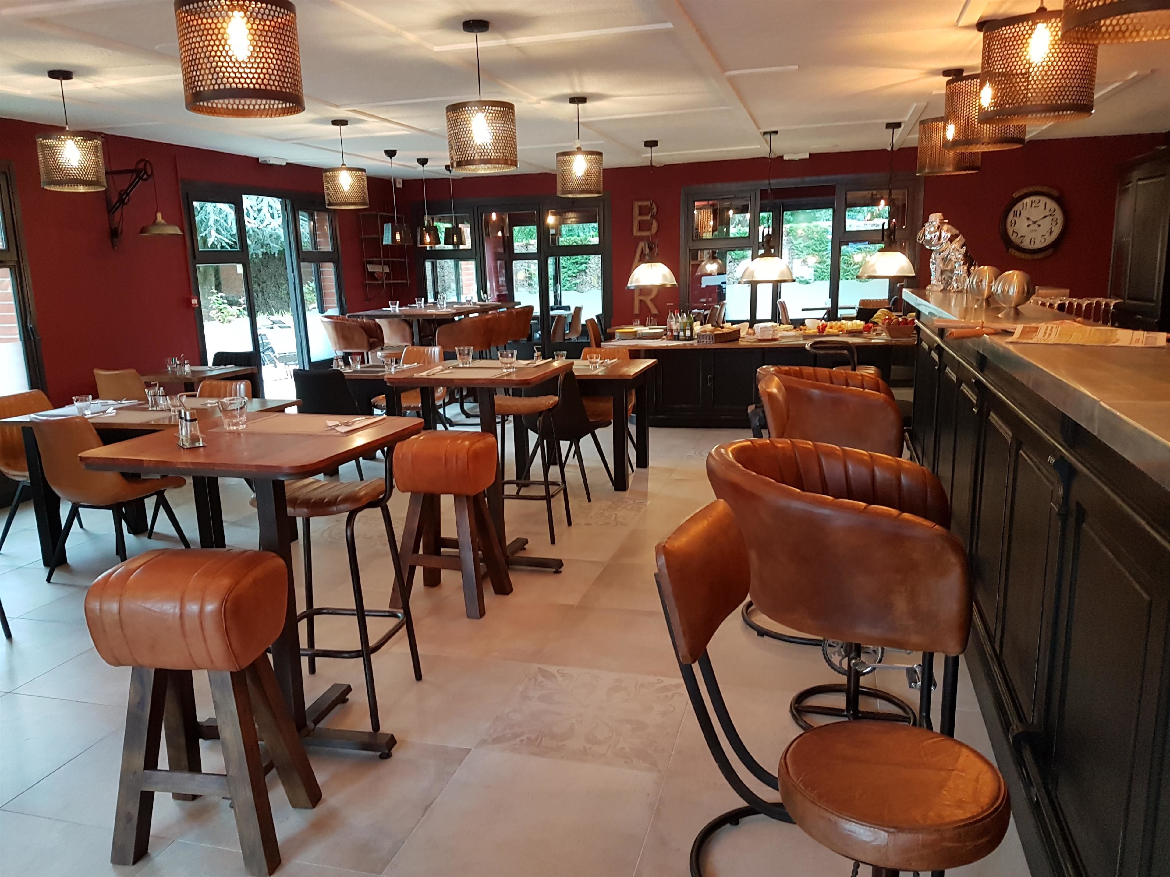 A restaurant with wooden tables and leather bar stools, large windows, and hanging pendant lights.