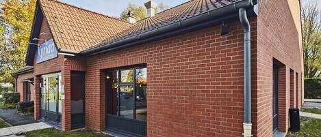 A brick building with a tiled roof, a reception area, and large windows.