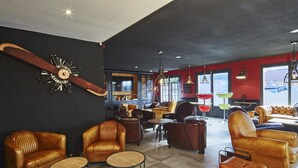 A modern lounge area with leather sofas, wooden tables, and a large clock on the wall. - Kyriad Lille Est - Hem (Hem)