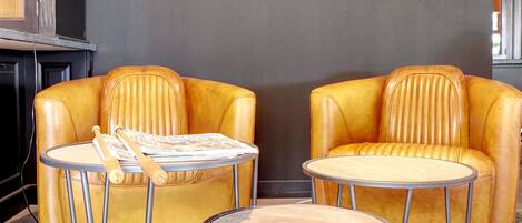 Un interior moderno con dos sofás de cuero amarillo, una mesa redonda y un reloj de pared singular.