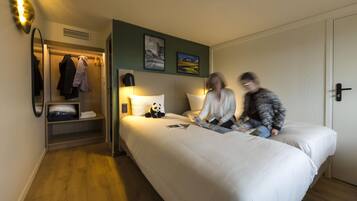 Una habitación de hotel con una cama grande, un armario, un espejo y dos cuadros colgados en la pared.