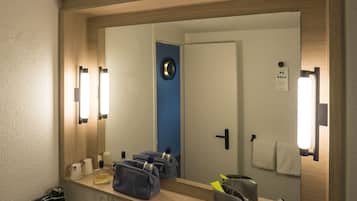 A bathroom with a large mirror, a towel rack, a soap dispenser, and a hairdryer.