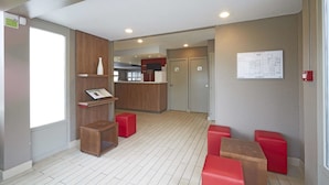 A modern hotel lobby with a reception desk, red seating, and a visible floor plan on the wall. - Campanile NATURE - Le Mans Est (Le Mans)