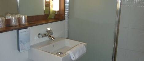 Un baño con un lavamanos blanco, un espejo y una ducha.