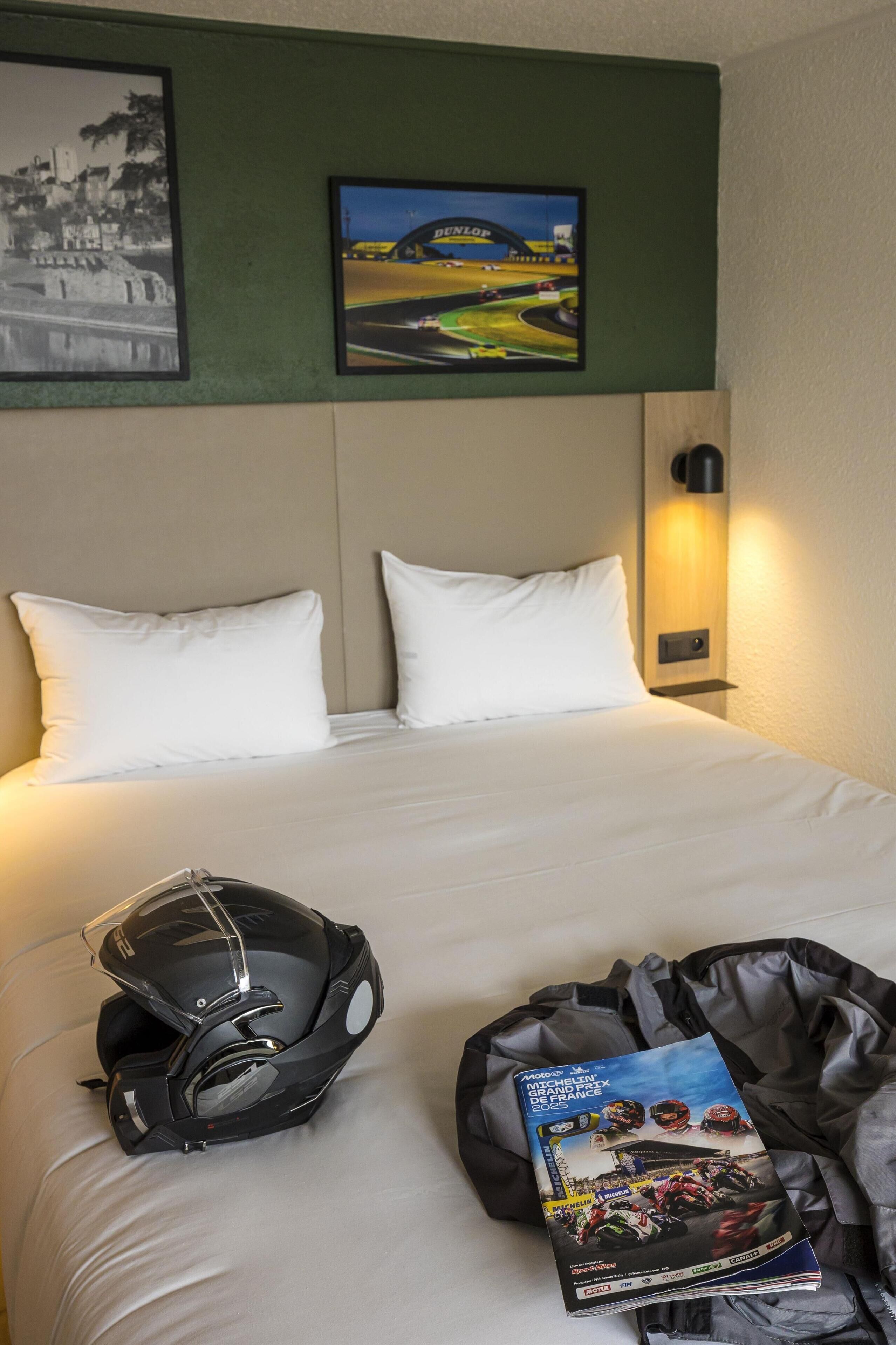 Une chambre d’hôtel avec un lit bien fait, un casque et un magazine posés sur le lit.