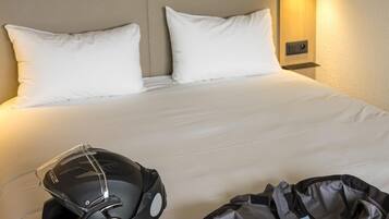 Quarto de hotel com uma cama bem arrumada, um capacete e uma revista sobre a cama.