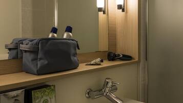 A hotel bathroom with a white sink, a mirror, and a towel dispenser.