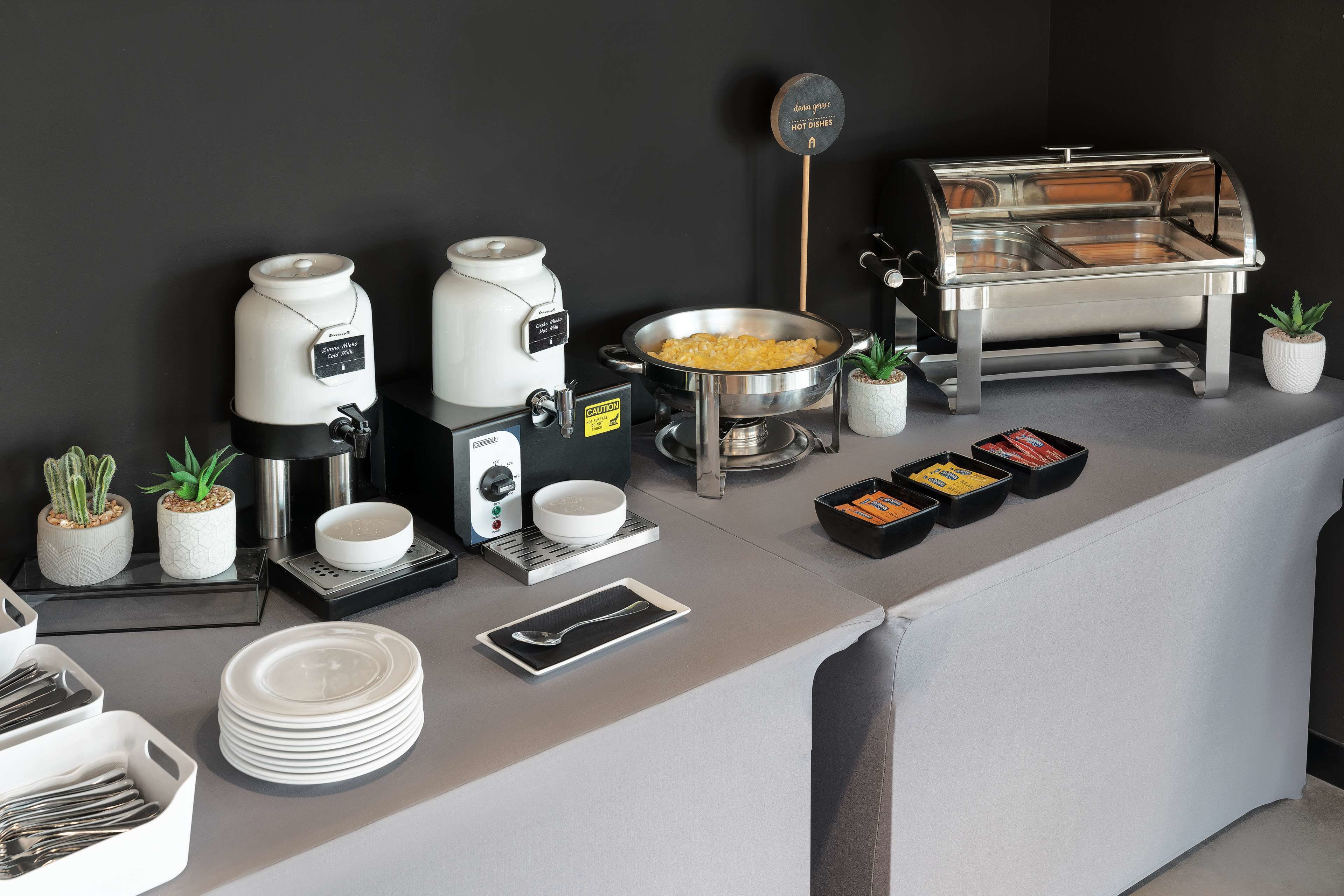 Un'area buffet con macchine per il caffè, un banco per pietanze calde e diversi contenitori per alimenti.