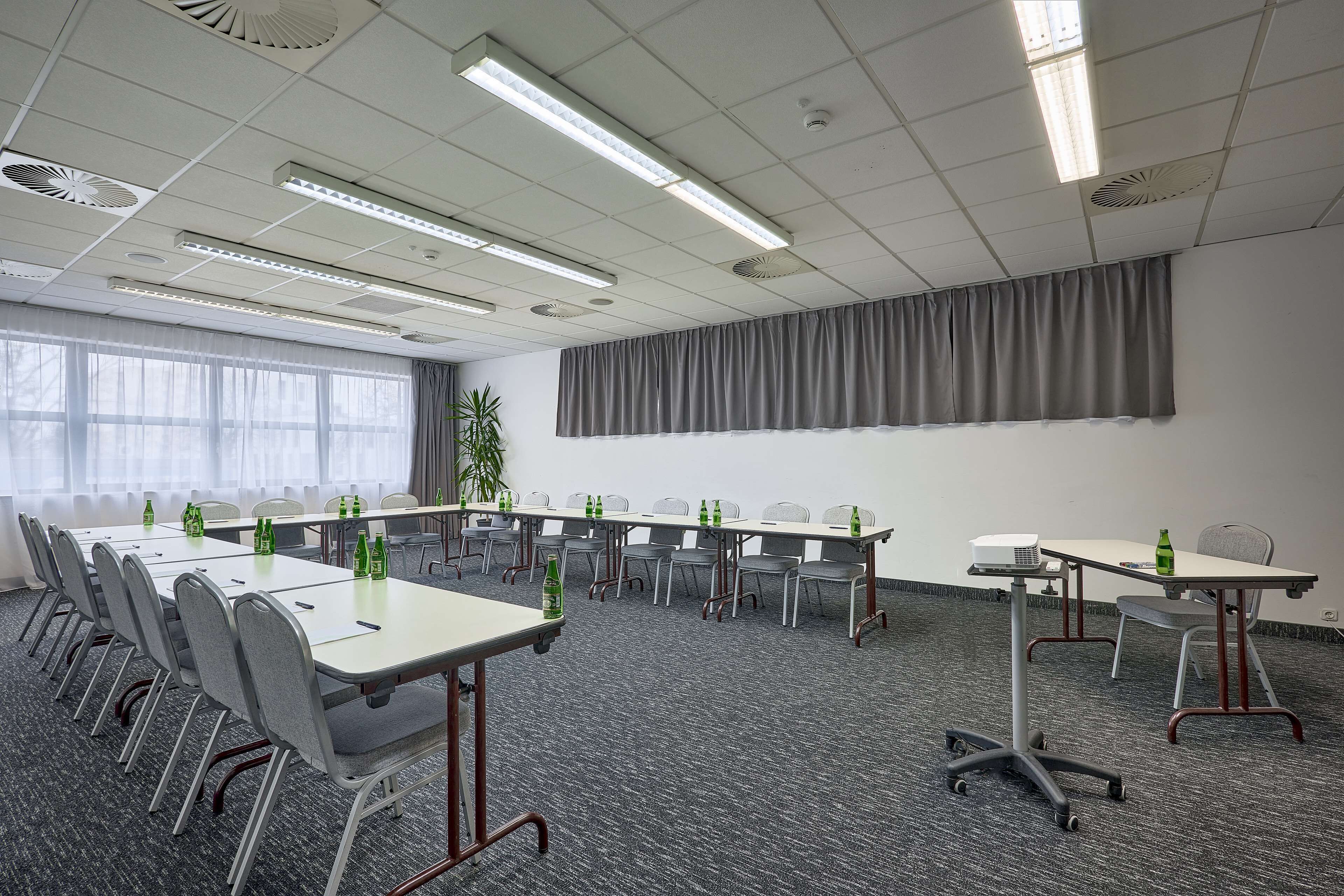 Un salón de conferencias con una larga mesa, sillas y un proyector.