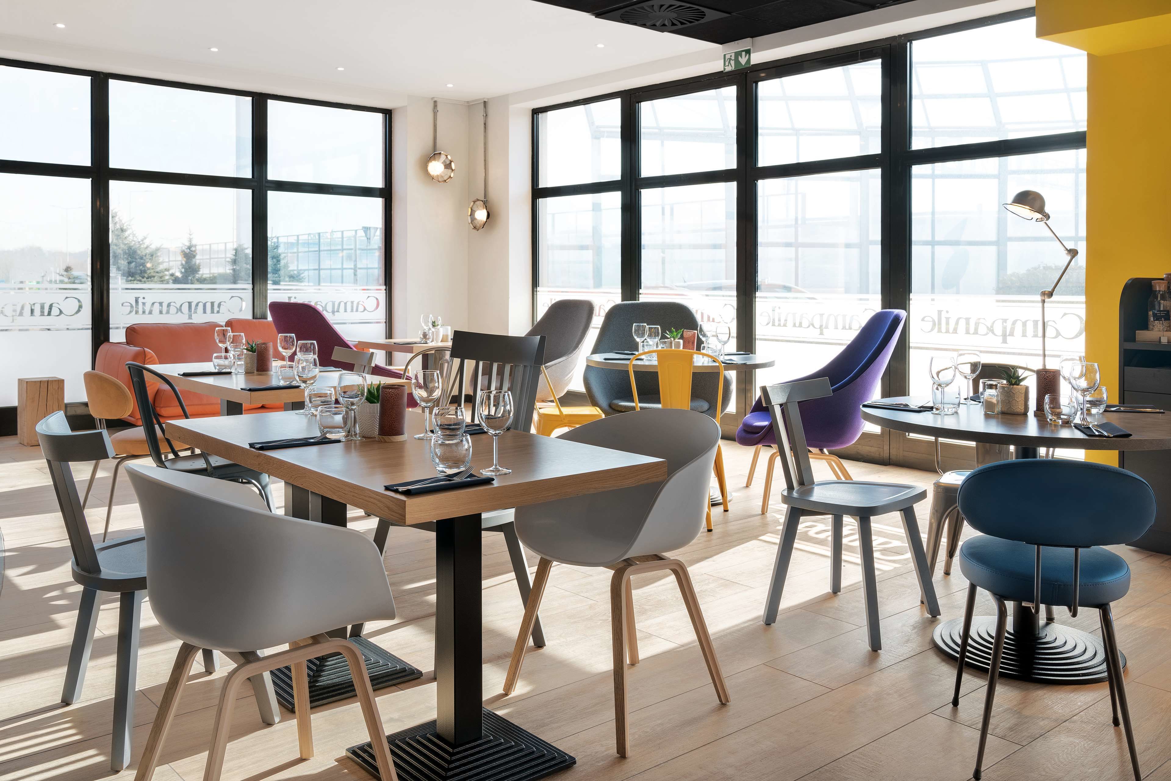 A modern dining area with multiple tables and chairs, large windows, and a view of the city.