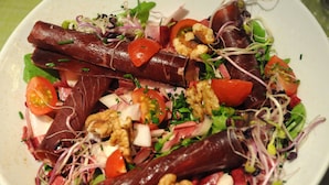 A plate of food with various ingredients including tomatoes, walnuts, and leafy greens. - Hôtel Inn Design Le Havre Nord Montivilliers (Montivilliers)