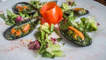 Een bord met mosselen, gegarneerd met tomaat en salade.