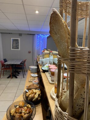 A buffet setup with various food items, including bread and pastries, arranged on a counter. - Hôtel Inn Design Le Havre Nord Montivilliers (Montivilliers)