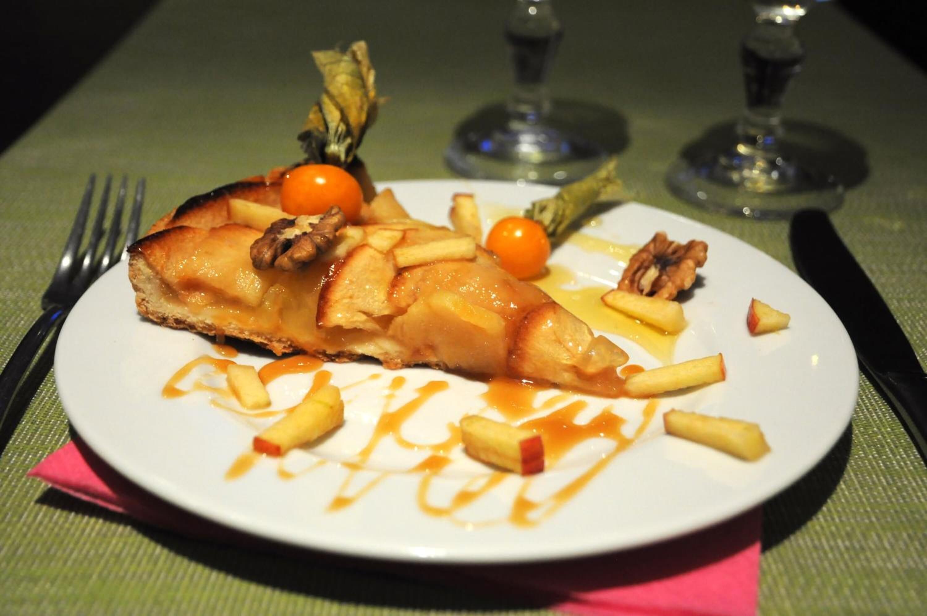 A plate with a slice of pie, cherry tomatoes, and a drizzle of sauce.
