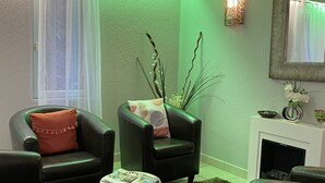 A modern living room with leather sofas, a small round table, and a fireplace. - Hôtel Inn Design Le Havre Nord Montivilliers (Montivilliers)