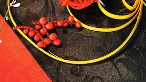 A decorative arrangement with a woven basket, red and yellow ribbons, and small red berries. - Hôtel Kyriad Lille Nord - Roncq (Roncq)