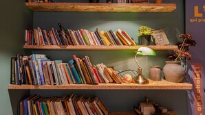 A bookshelf with multiple shelves filled with books, a green desk lamp, and decorative items. - Birgit Hotel Le Havre Centre (Le Havre)