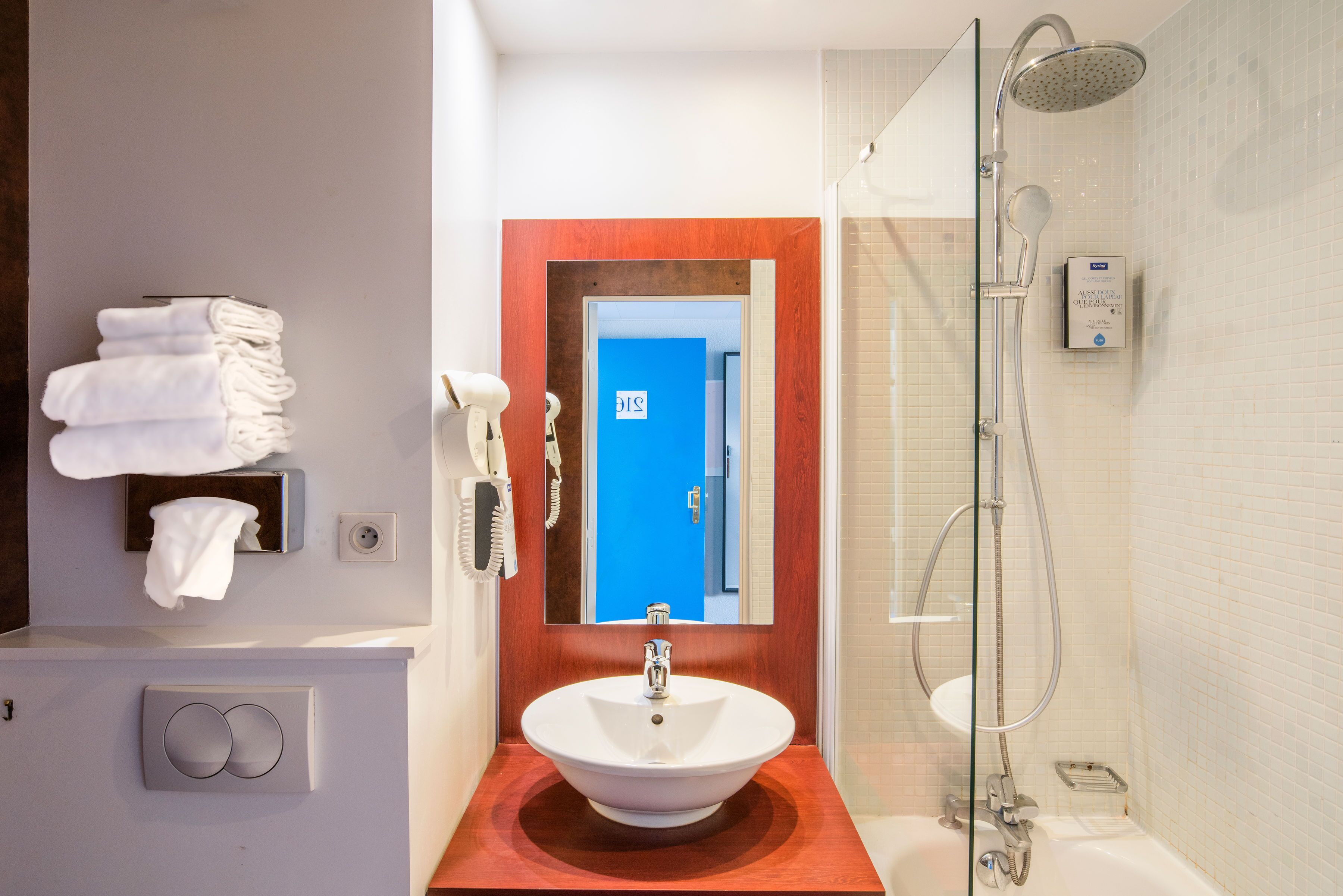 Une salle de bain équipée d’un lavabo, d’un miroir, d’un porte-serviettes et d’une douche.