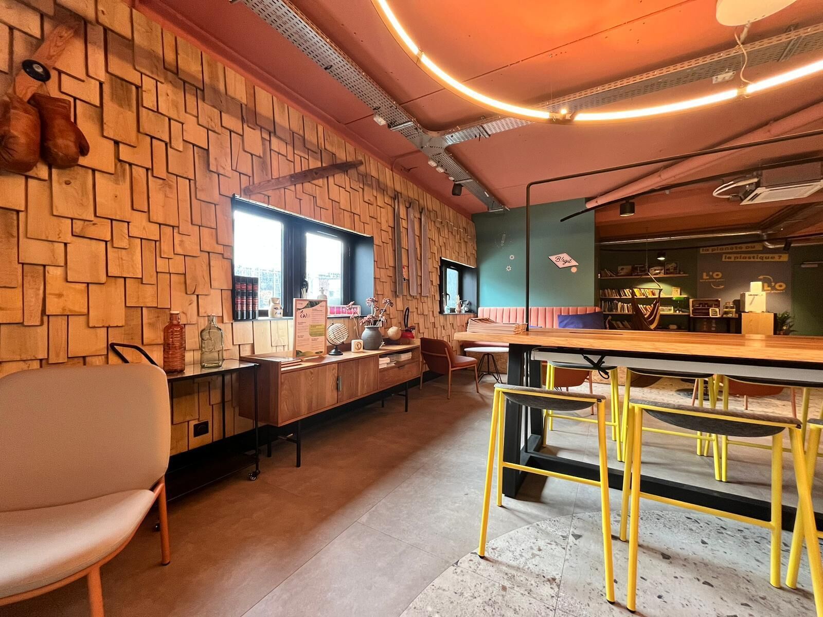 Un café chaleureux avec un mur en bois, un comptoir où est affiché le menu, et un espace où sont disposées des chaises et des tables.