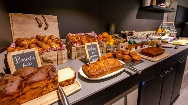 A bakery display with various baked goods and a chalkboard sign. - Birgit Hotel Le Havre Centre (Le Havre)